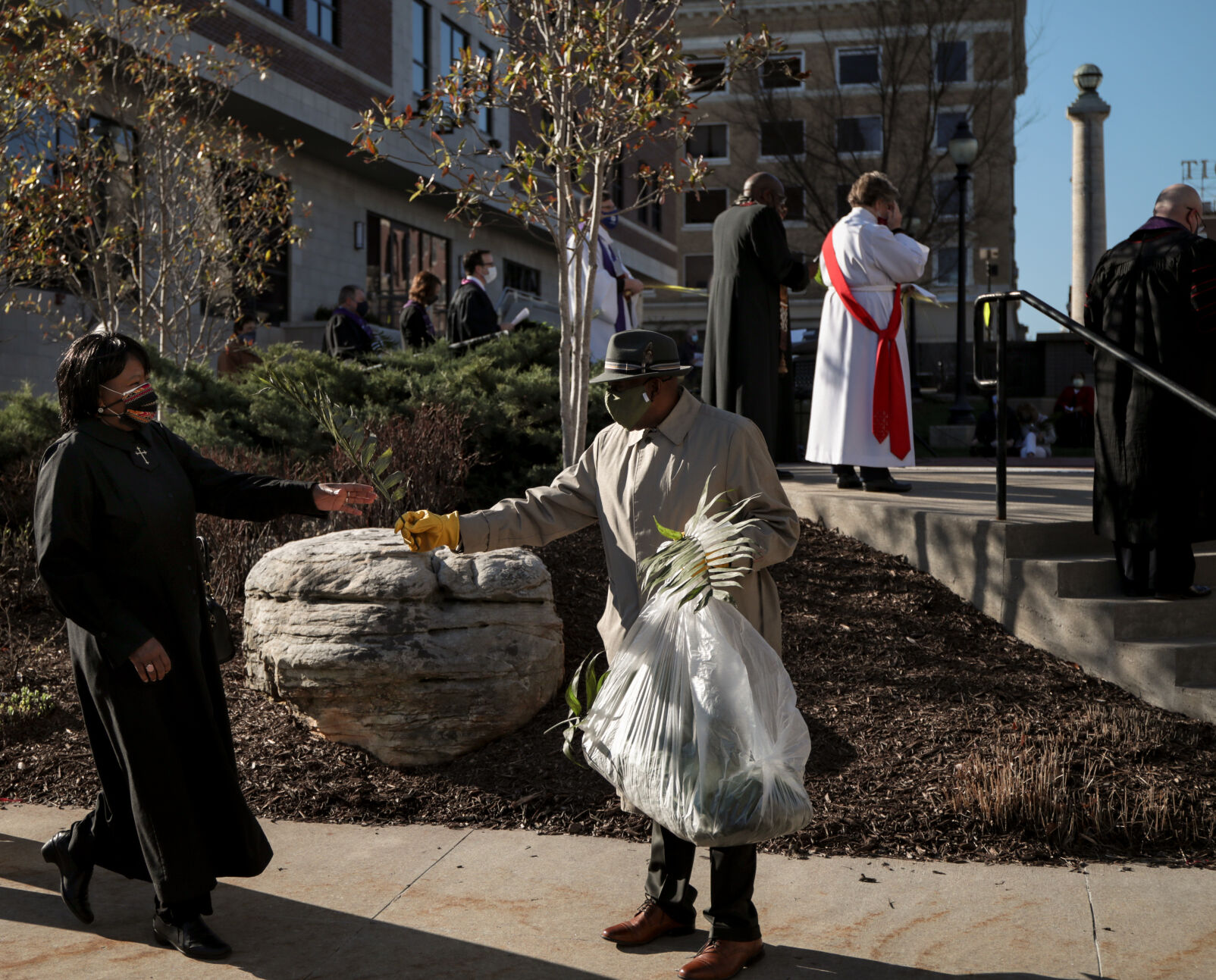 A women, left, reaches to accept a palm frond from a man